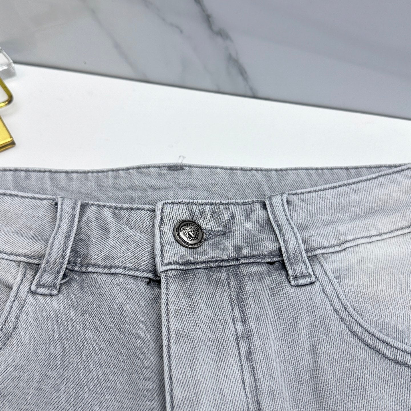 Light-wash jeans waistband with small metal logo patch