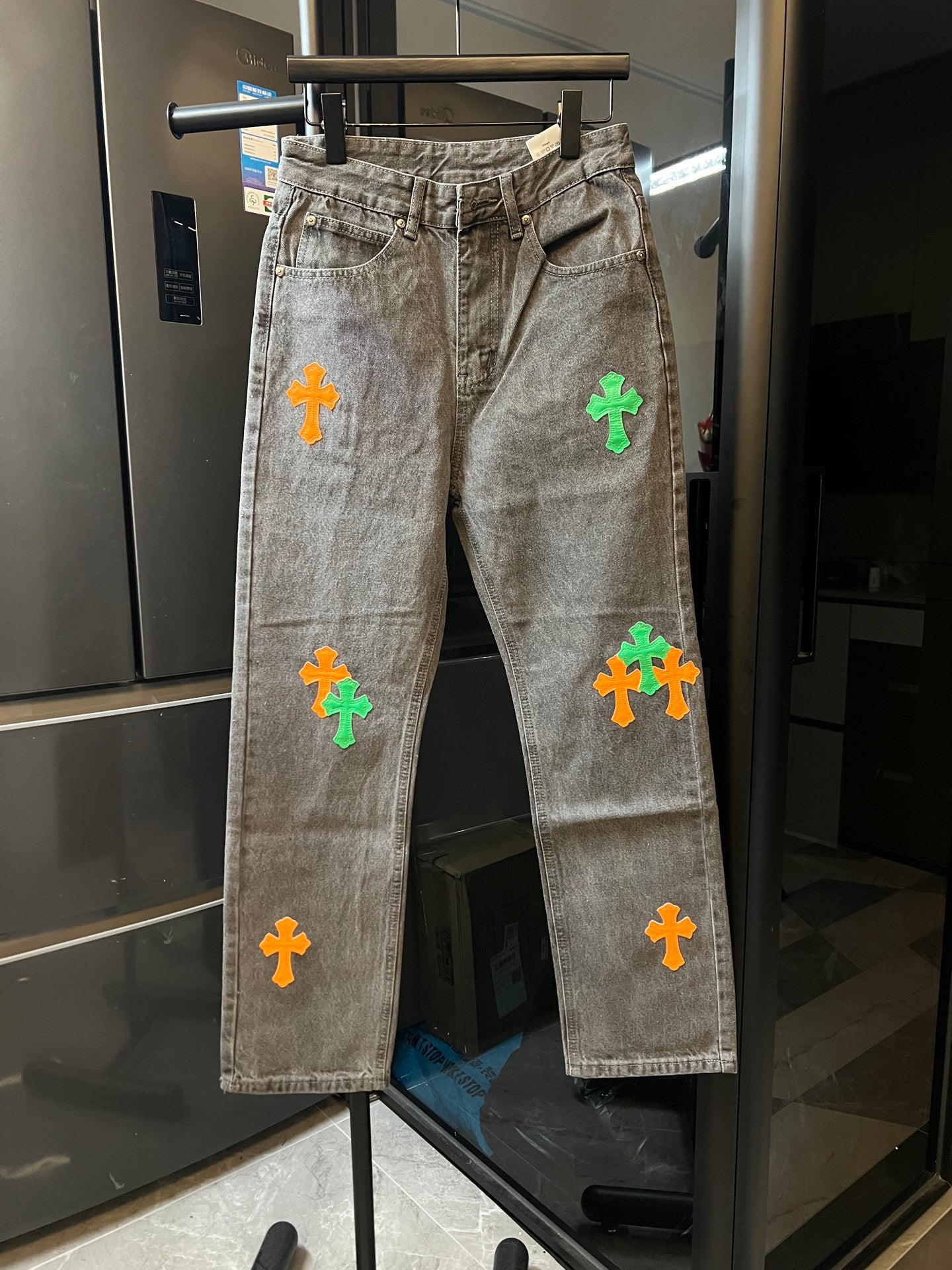 Light gray denim pants with colorful cross patches on the legs