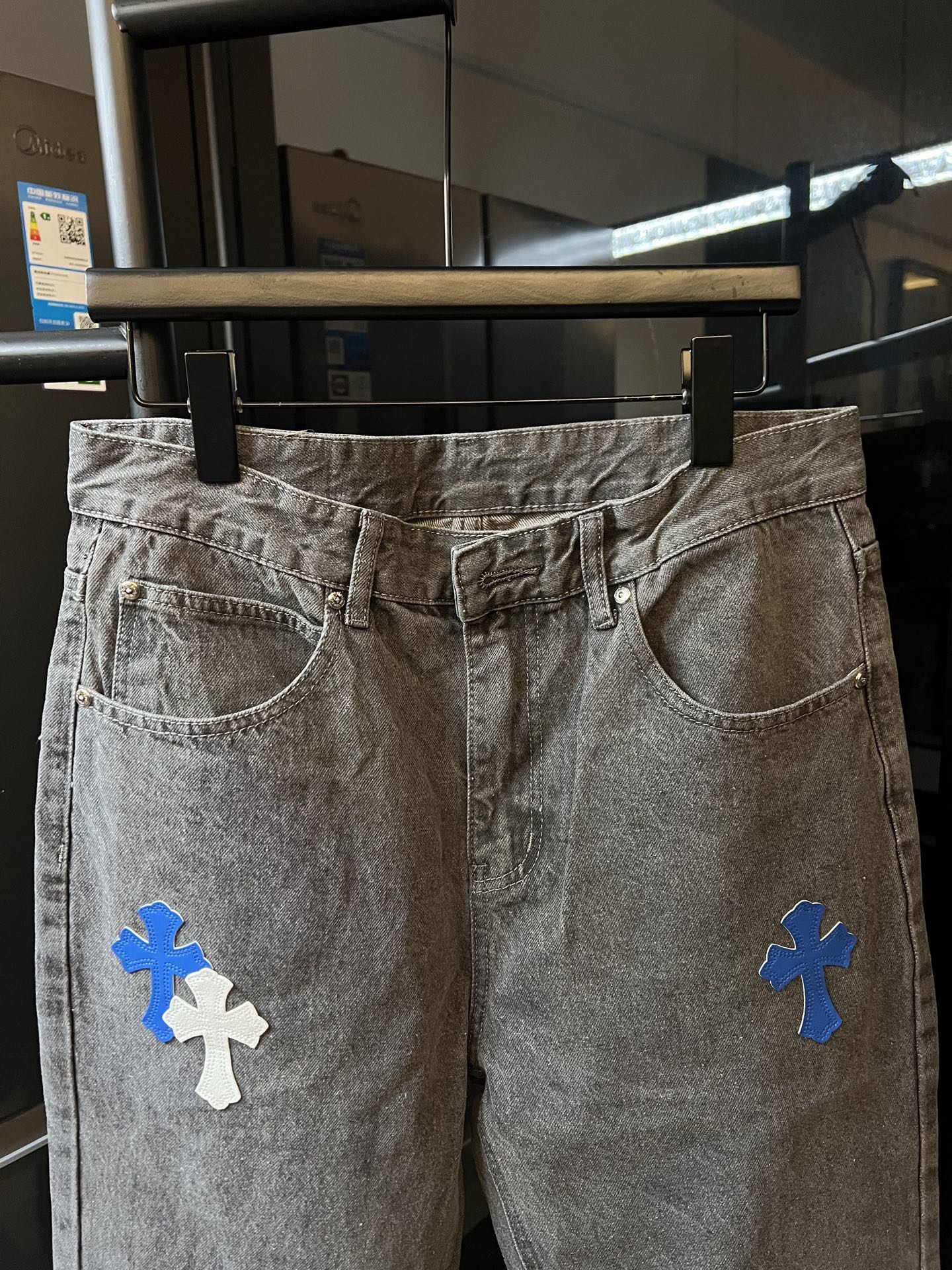 Light gray denim pants with blue cross embroidery, front pockets and waistband