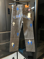 Light gray denim pants with blue cross patches and printed lettering across front