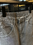 Light gray denim pants with belt loops and buttoned fly, blue cross patch detail