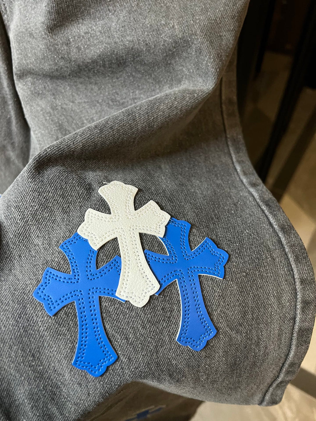 Light gray denim fabric with blue and white cross appliques on knee area