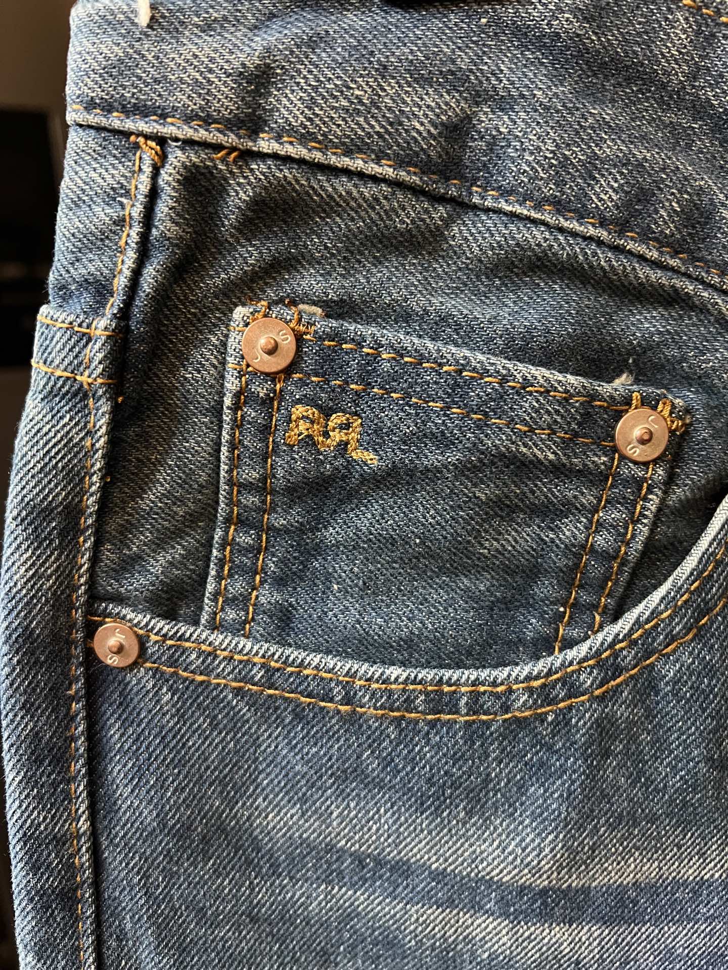 Light blue denim jeans with stitched coin pocket and copper-tone buttons
