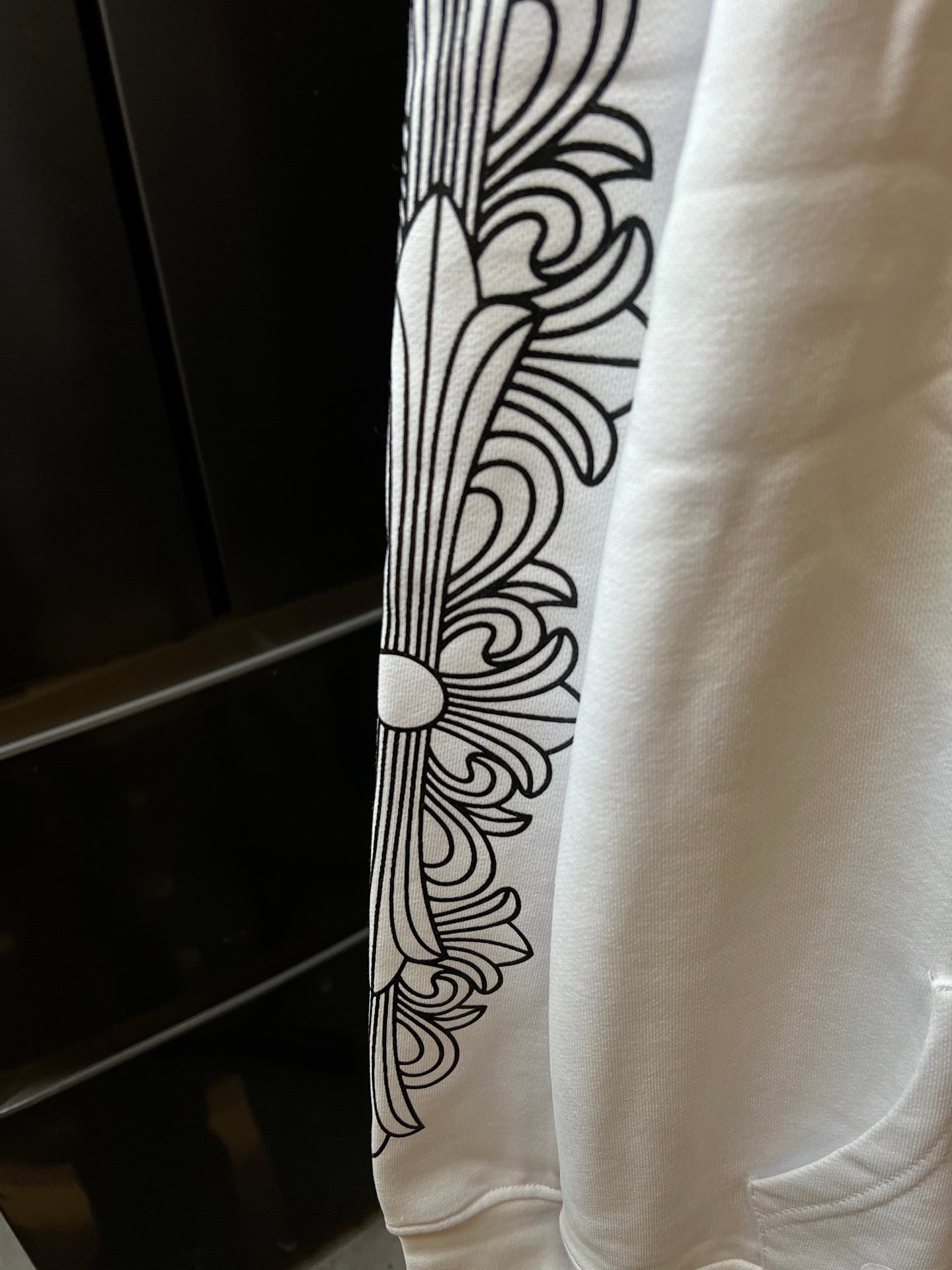 Light cream hoodie sleeve with black line-art floral pattern.