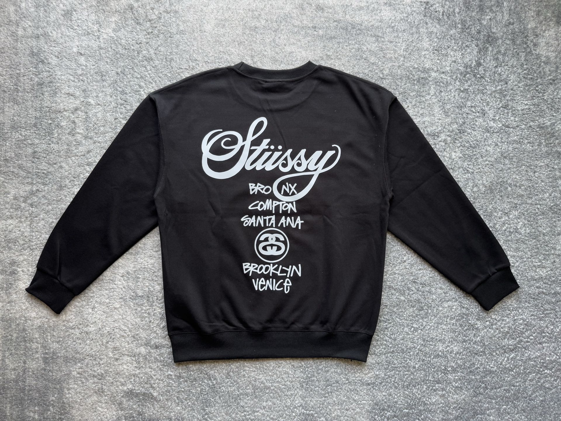 Stussy crewneck sweatshirt, dark with white logo and city list on back