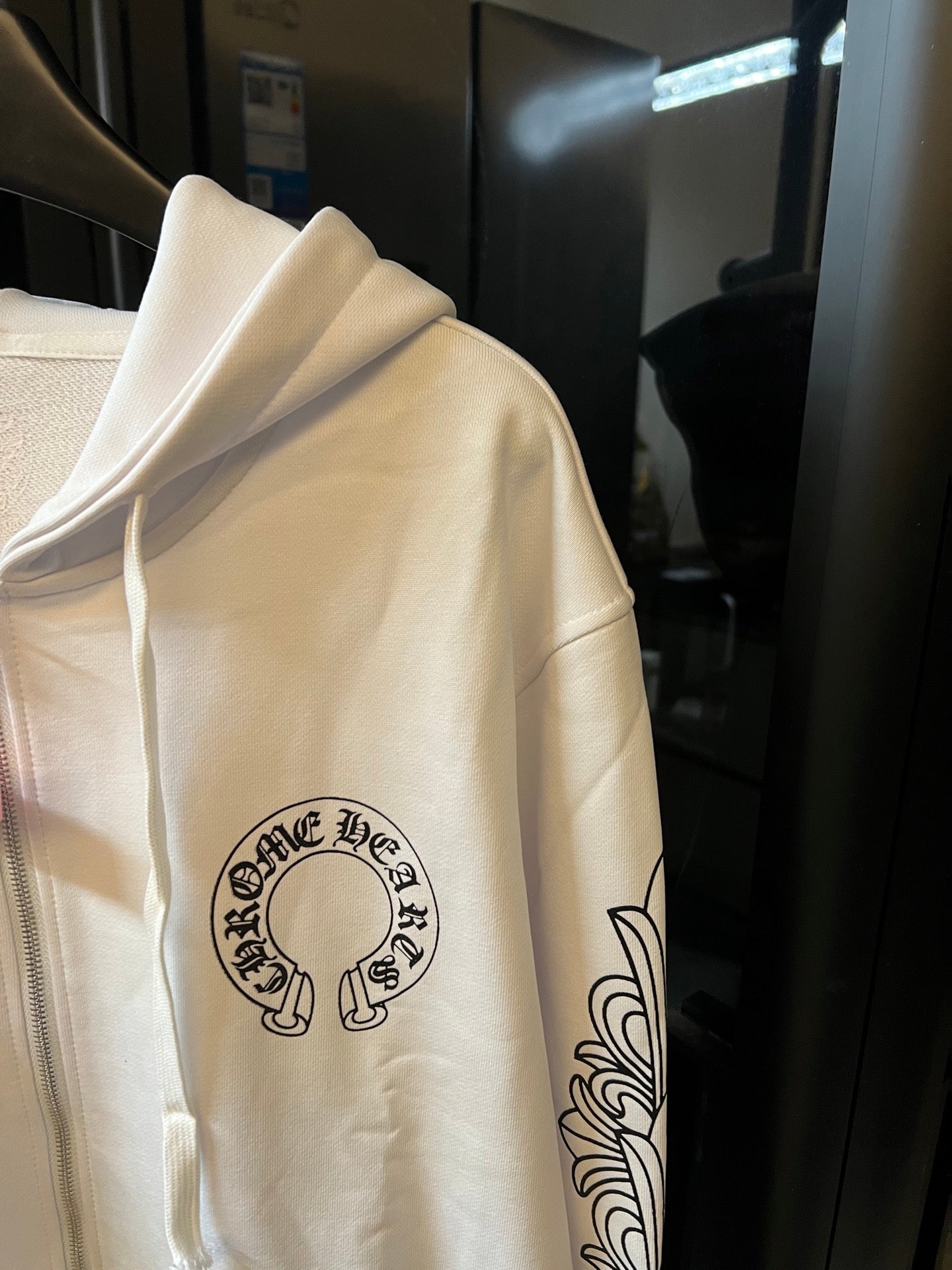 Light cream zip-up hoodie sleeve with black graphic logo print.