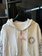 Light cream zip-up hoodie close-up with hood drawstrings and chest emblem.