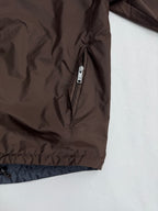 Brown jacket front with silver zipper and blue-lined cuff hem