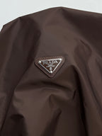Brown jacket shoulder with triangular Prada logo patch detail