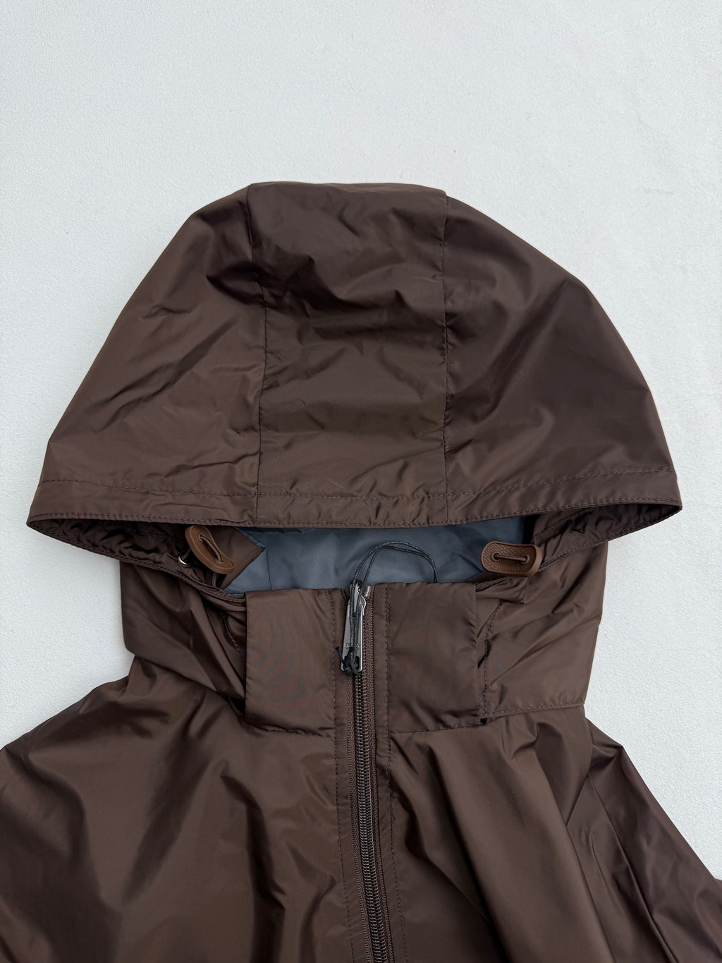 Long hooded jacket with full front zipper, brown shell and blue lining at hem