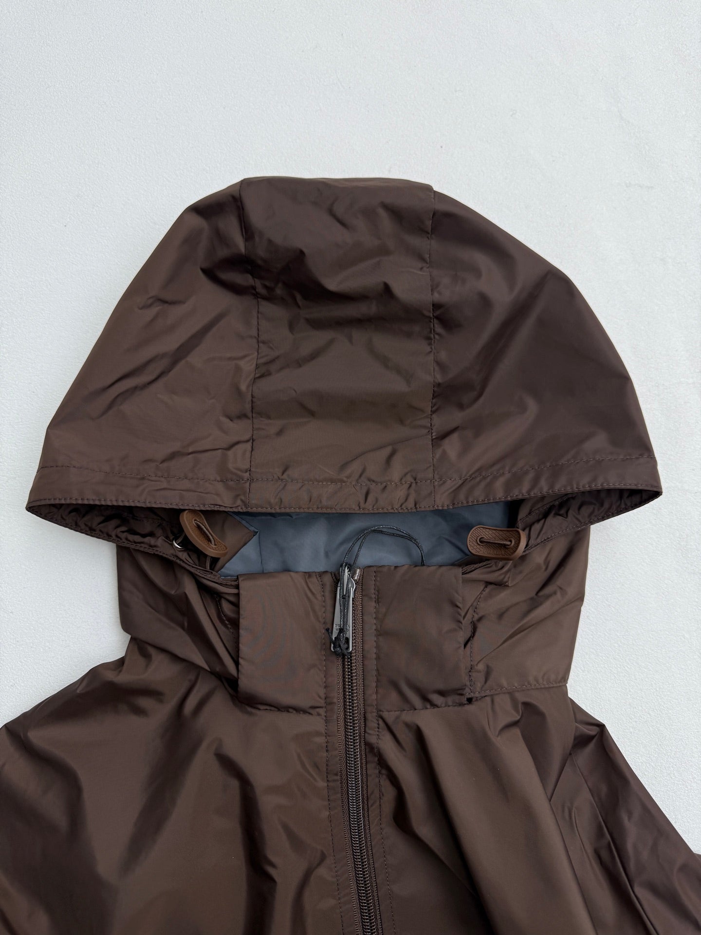 Long hooded jacket with full front zipper, brown shell and blue lining at hem