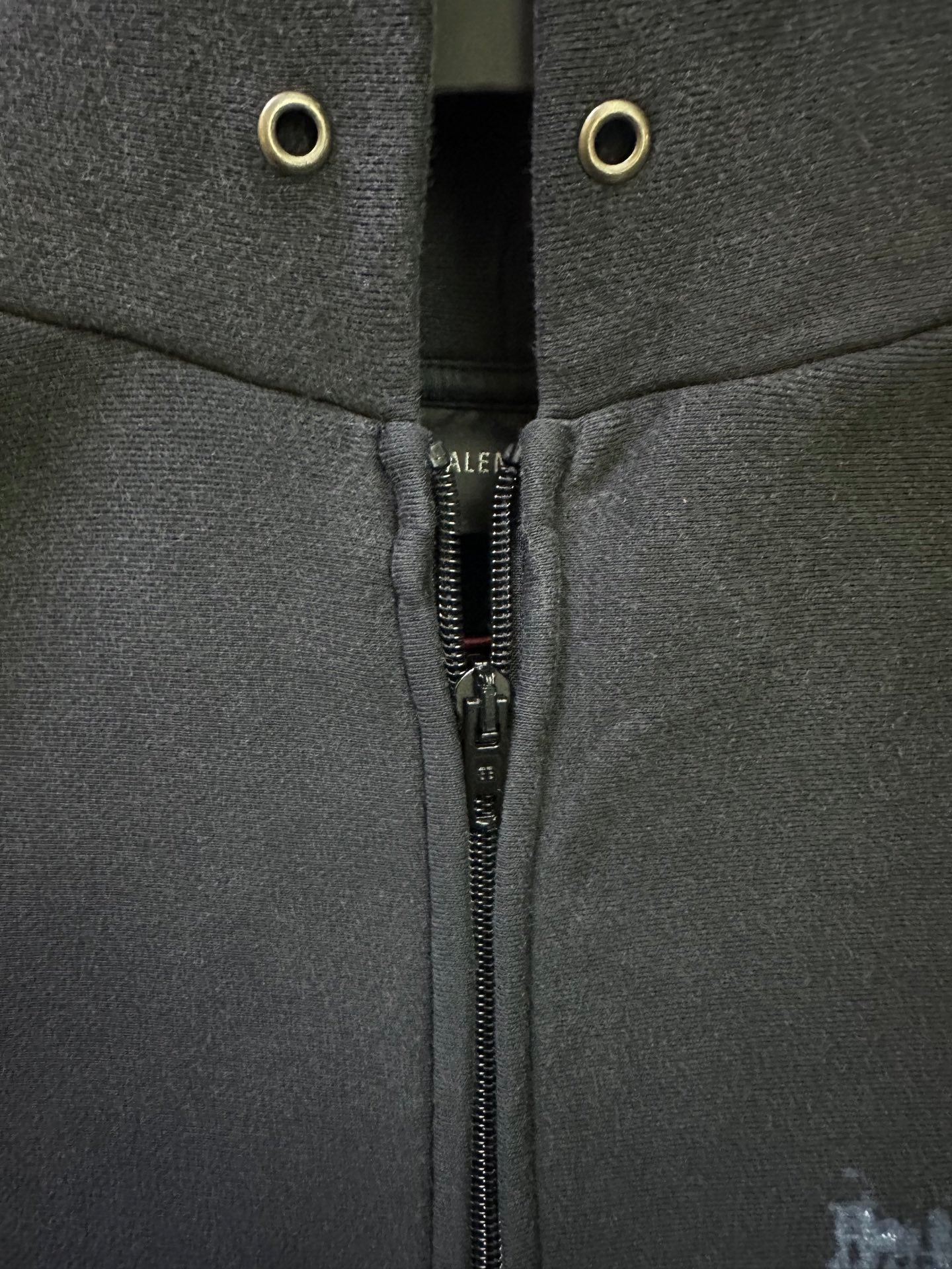 Dark hoodie neckline with metal grommets and visible center zipper