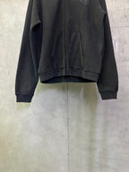 Dark zip-up hoodie front with two pockets and gathered fabric at hem