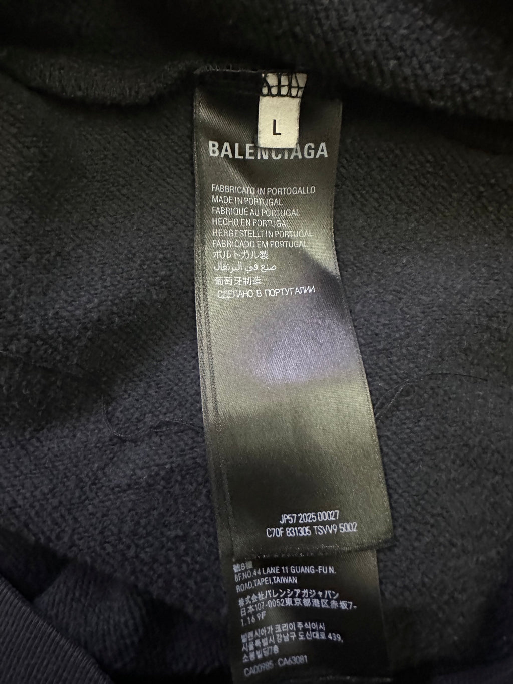 Inside neck label on dark hoodie with size and brand information