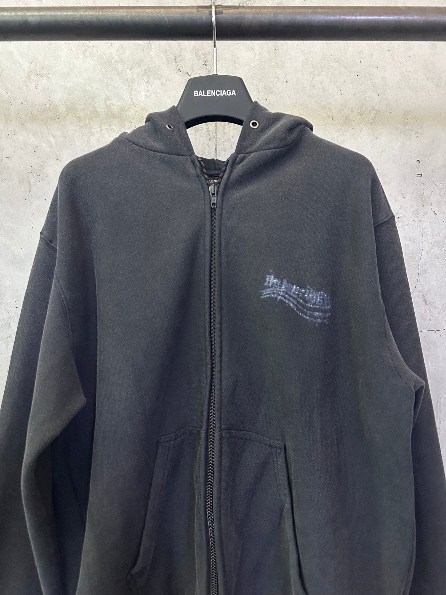 Dark zip-up hoodie with hood, center zipper, and small chest logo print