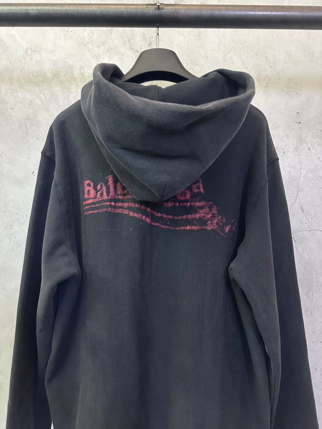 Dark hoodie with hood and large red Balenciaga logo print across back