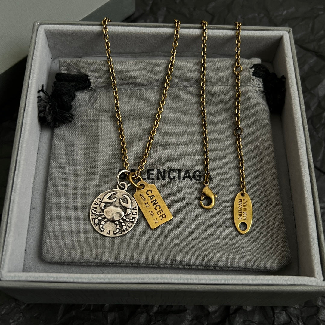 Gold chain necklace with circular silver charm and gold Cancer tags in gift box