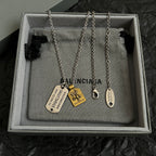 Balenciaga charm necklace with multiple dog-tag pendants on jewelry pouch in box