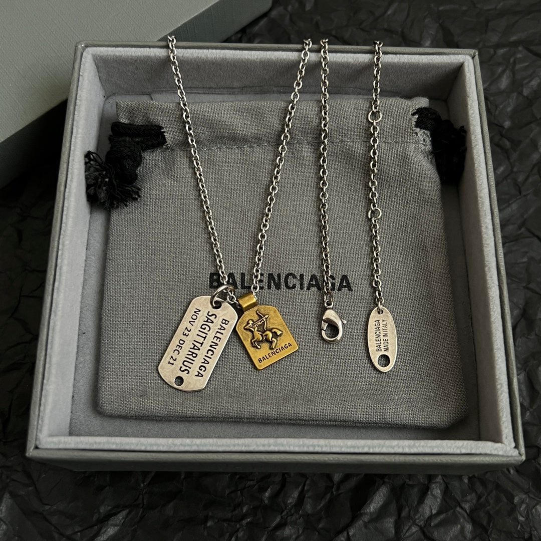 Balenciaga charm necklace with multiple dog-tag pendants on jewelry pouch in box