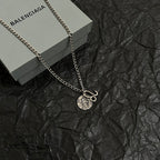 Balenciaga charm necklace with round logo pendant and hook charm on chain