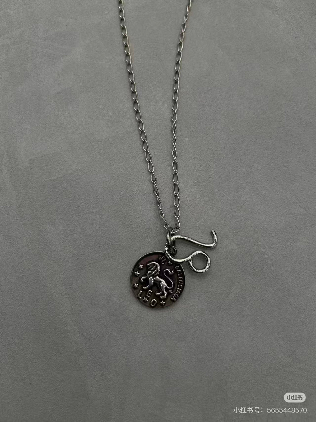 Balenciaga charm necklace close-up: round logo pendant with lettering on chain