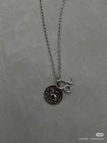 Balenciaga charm necklace close-up: round logo pendant with lettering on chain