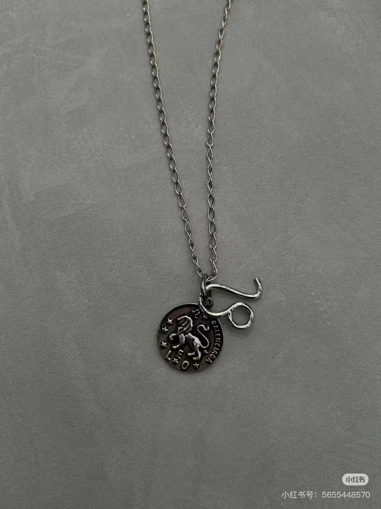 Balenciaga charm necklace close-up: round logo pendant with lettering on chain