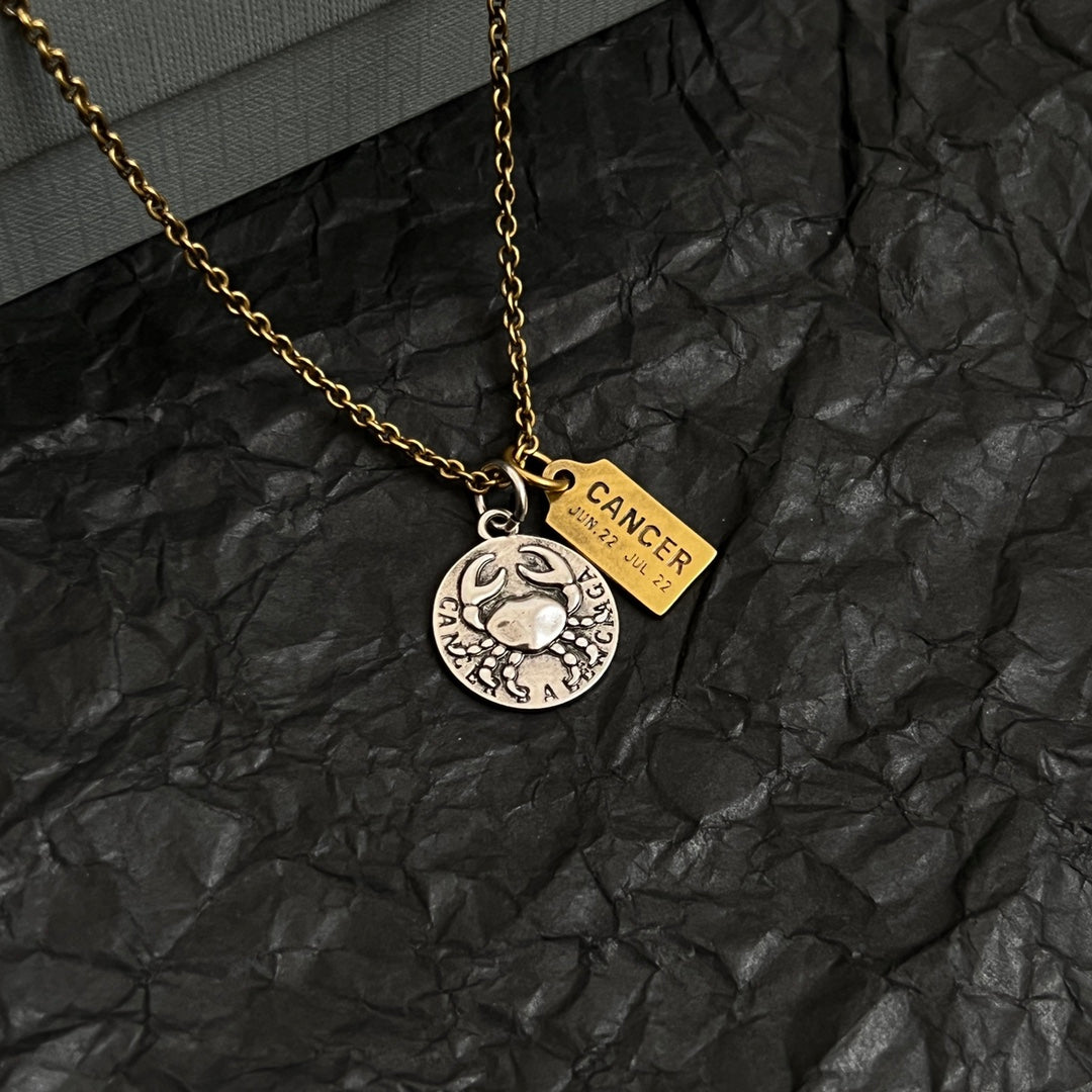Gold chain necklace with circular silver medallion and gold Cancer charm tag