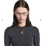 Model wearing a gold chain necklace with round silver medallion and Cancer charm