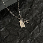 Silver necklace pendant with animal claw charm and engraved rectangular tag