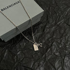 Silver chain necklace with rectangular tag and animal claw charm pendant