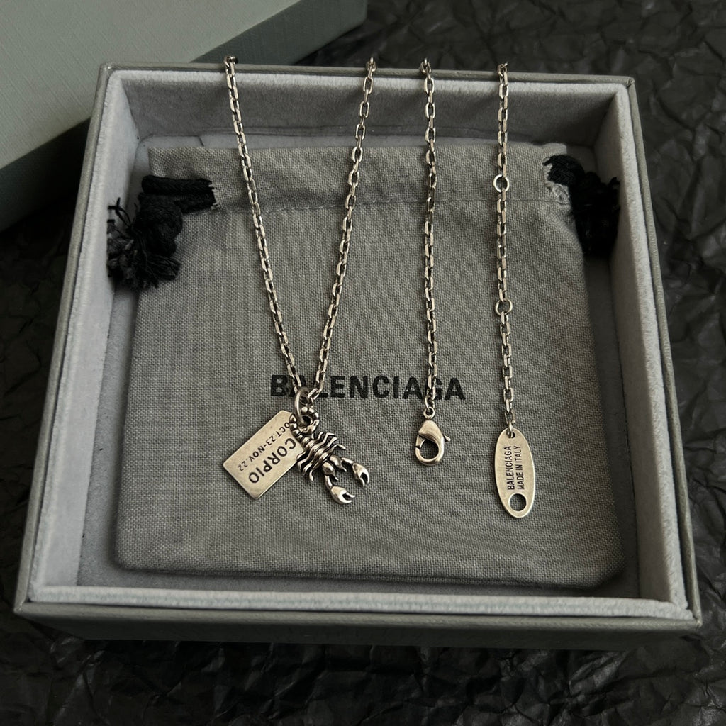 Accessory box display with four silver chain necklaces, each with charm and tag