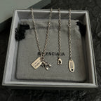 Accessory box display with four silver chain necklaces, each with charm and tag