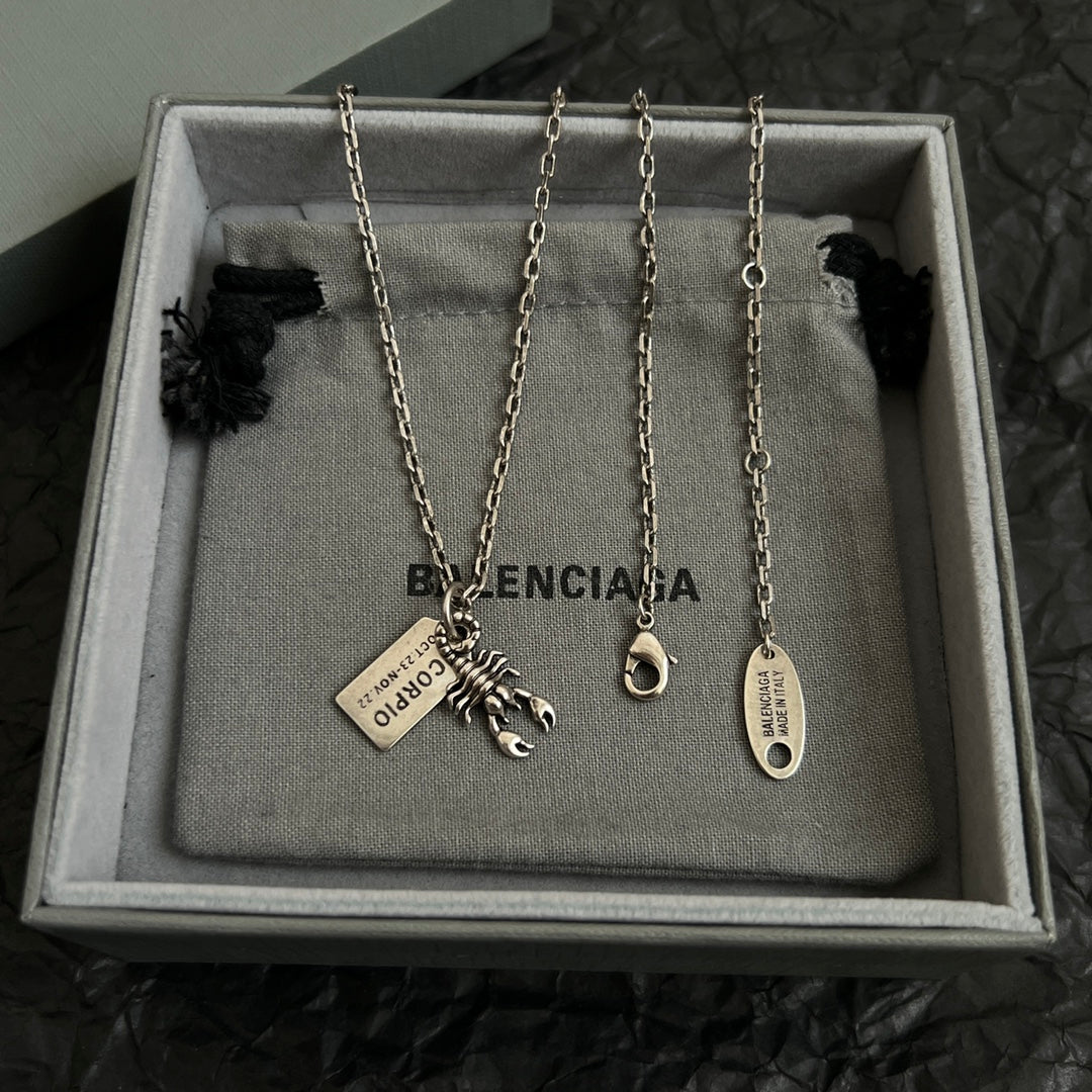 Accessory box display with four silver chain necklaces, each with charm and tag