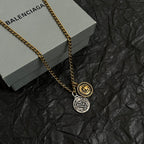 Gold-tone charm necklace close-up with two circular pendants on a link chain