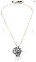 Gold charm necklace with circular zodiac coin pendant and hanging engraved tag
