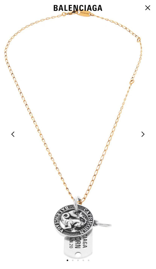 Gold charm necklace with circular zodiac coin pendant and hanging engraved tag