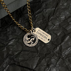 Gold charm necklace with circular zodiac coin and beige engraved name tag