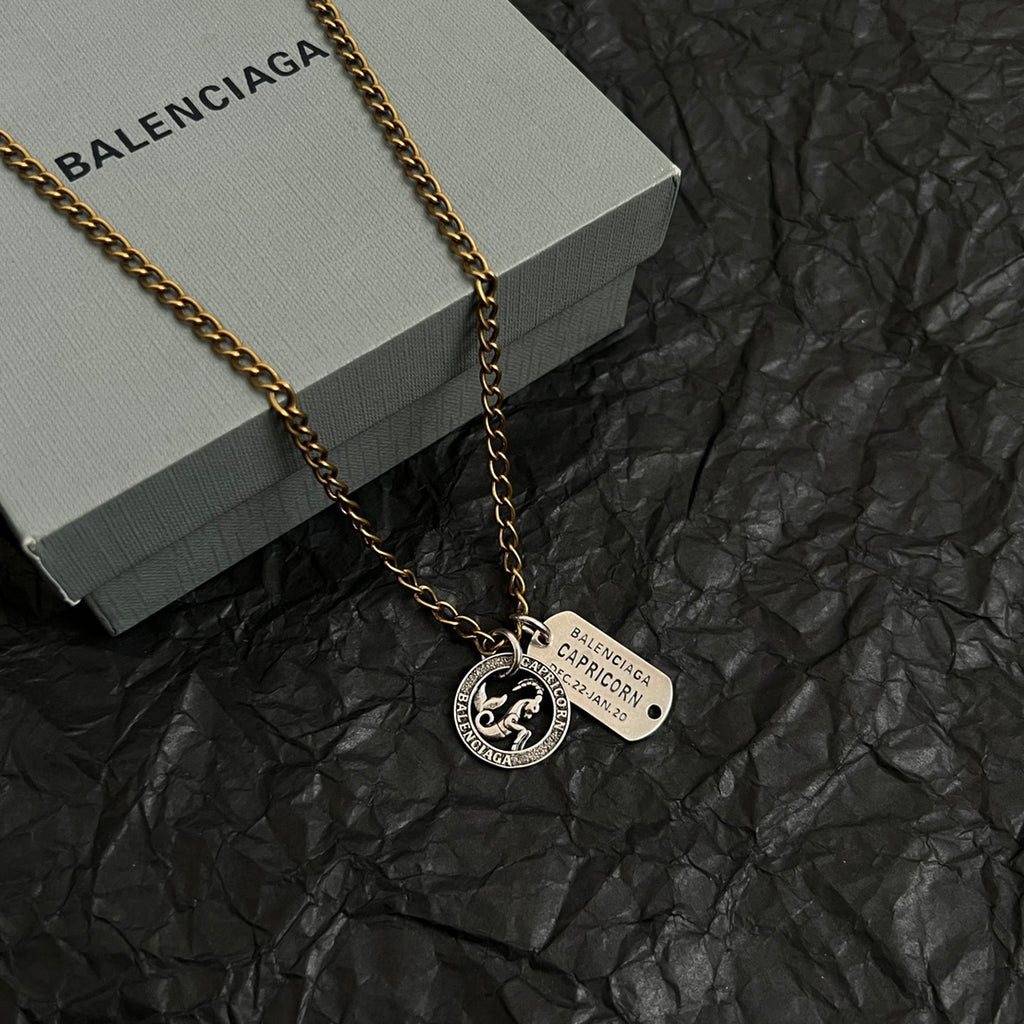 Gold charm necklace with zodiac coin pendant and engraved rectangular tag
