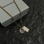 Gold charm necklace with zodiac coin pendant and engraved rectangular tag