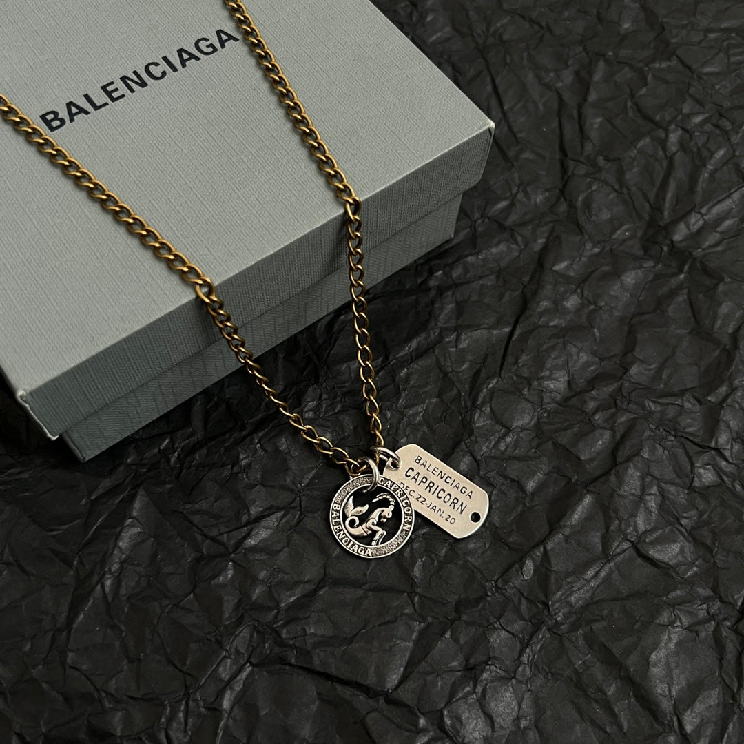 Gold charm necklace with zodiac coin pendant and engraved rectangular tag