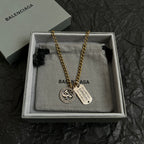 Balenciaga charm necklace with zodiac coin, engraved tag, and gold chain