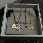 Balenciaga gold-tone charm necklace set with circular pendant and hanging tags