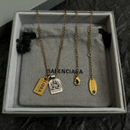 Gold-tone charm necklace in a gift box with multiple tag pendants