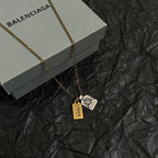 Gold-tone charm necklace with two tag pendants on a chain