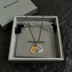 Gold-tone charm necklace with Balenciaga logo pendants in a gift box