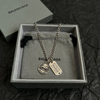 Balenciaga charm necklace with two pendants and chain, shown in gift box