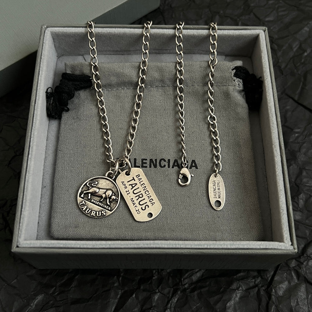 Balenciaga charm necklace in box with two round pendants and oval tag charm