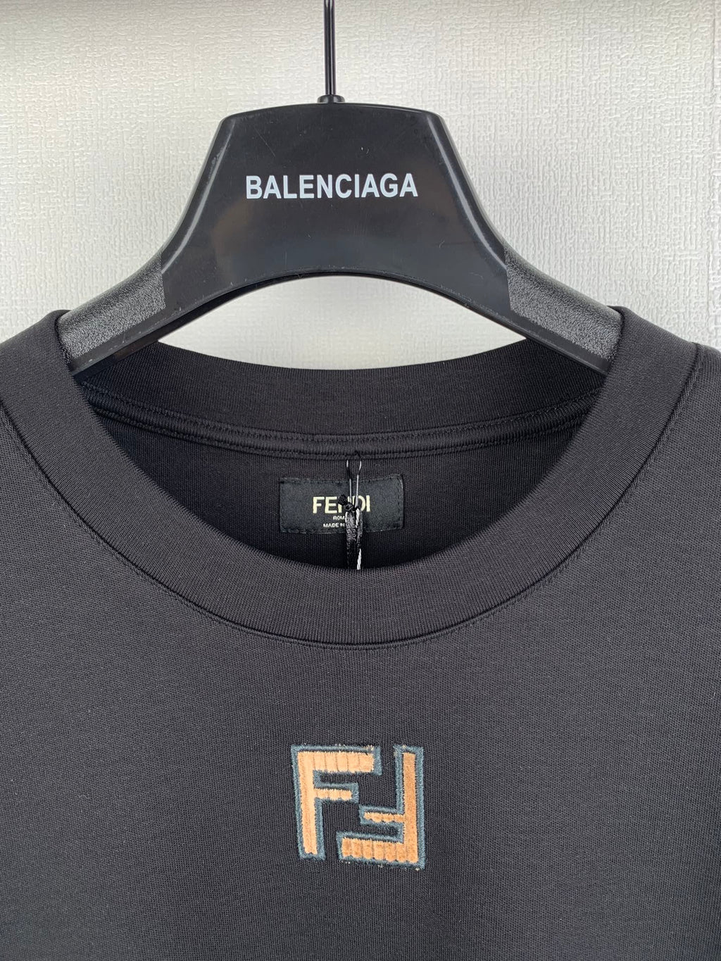 Fendi T-shirt neckline close-up with embroidered square logo at chest.