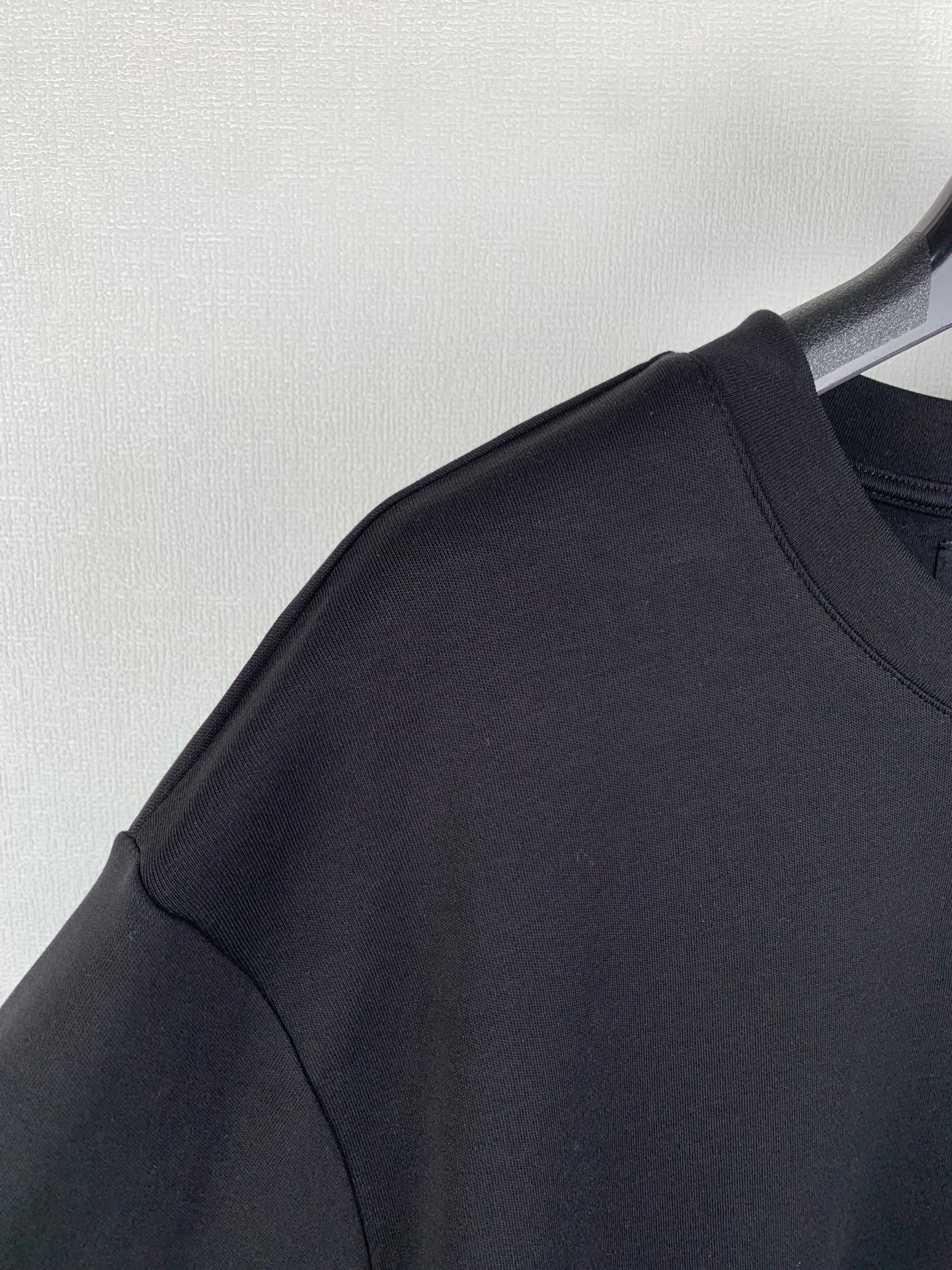 Fendi T-shirt shoulder and sleeve seam detail on dark gray/black fabric.